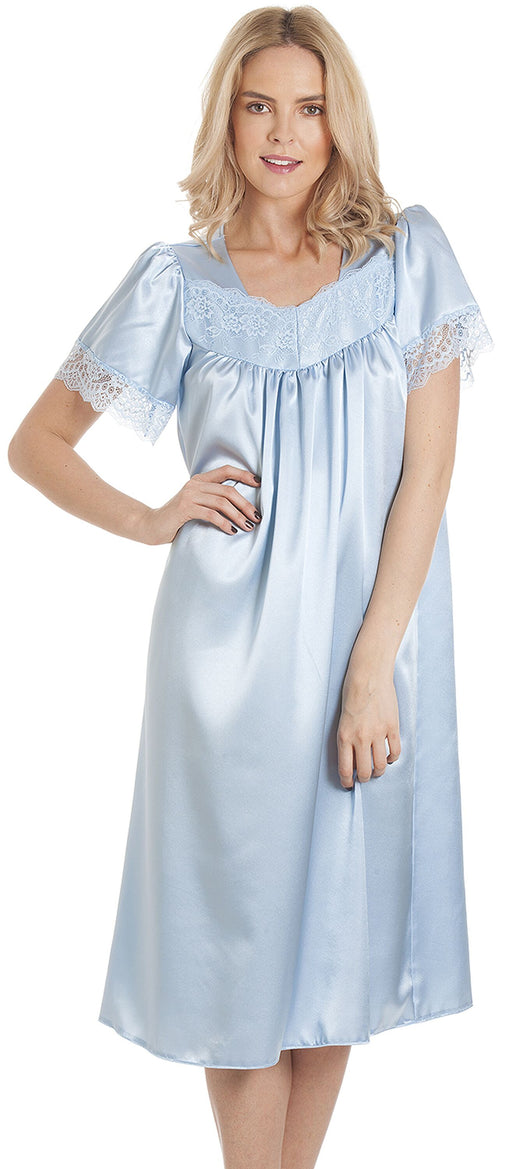 A blonde woman models a pale blue satin nightdress with short sleeves, a square neckline, and lace trim. 
